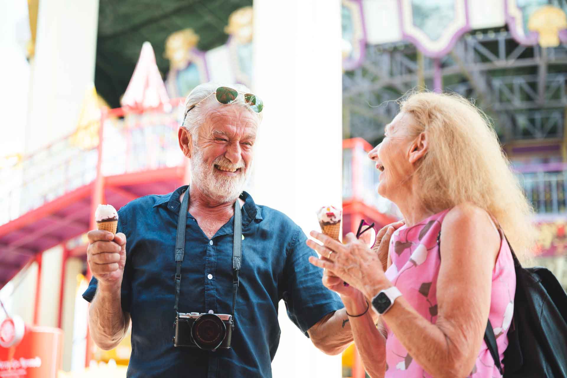 Happy senior couple eating ice cream at amusement park
